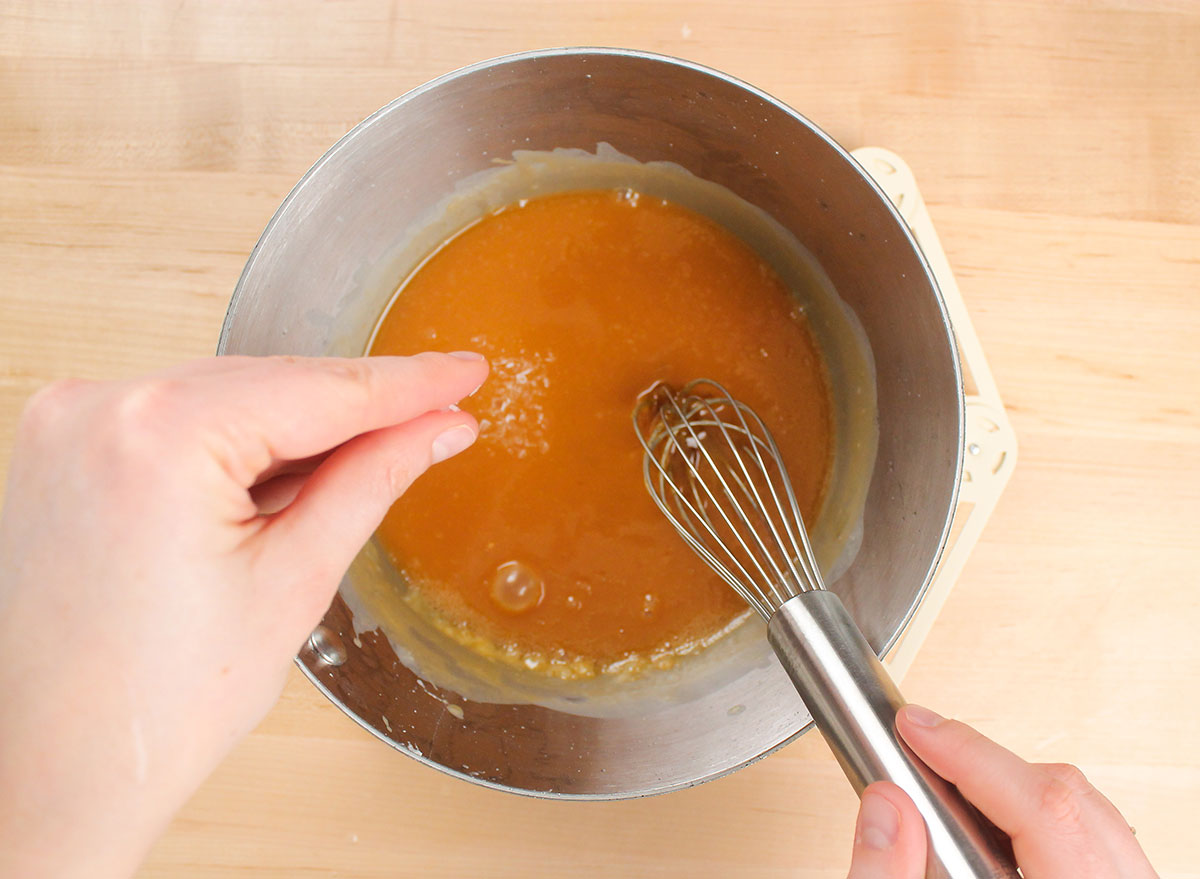 adding salt to caramel in a pot