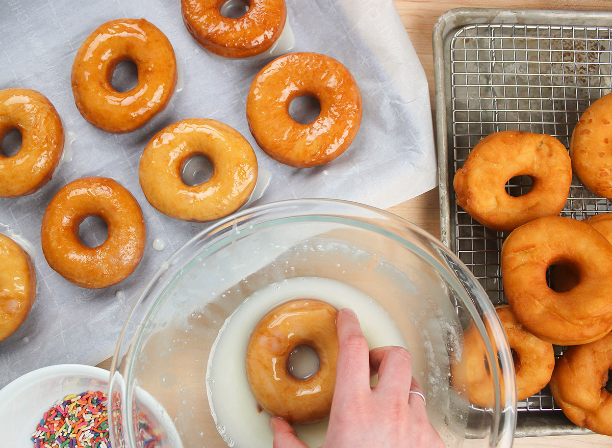 dipping hot donuts into a glaze