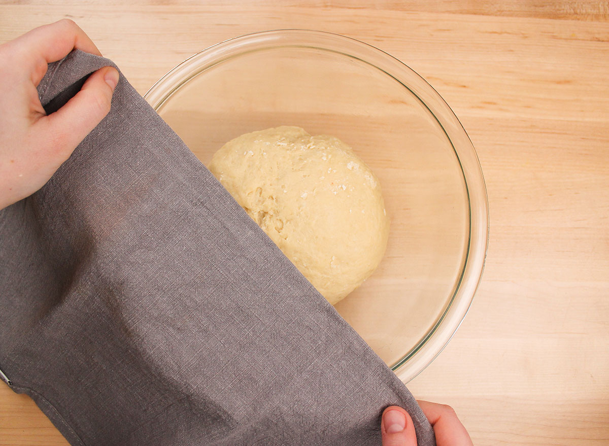 covering a ball of dough with a kitchen towel