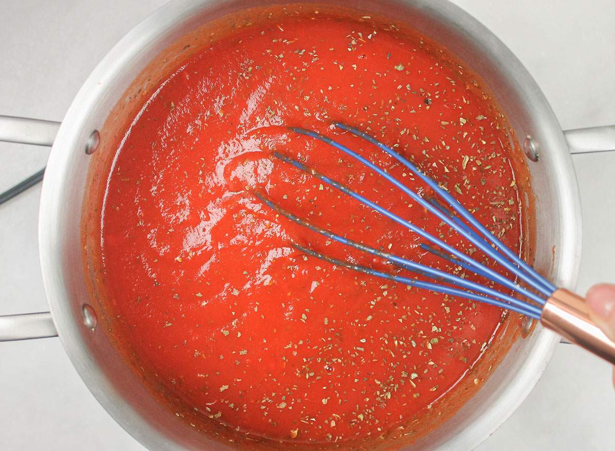 whisking tomato sauce with herbs