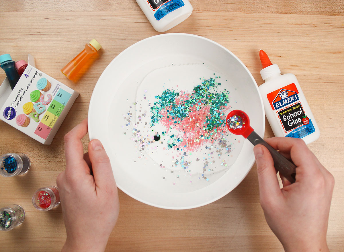 adding glitter to glue and water mixture in a bowl