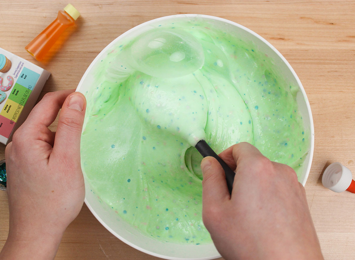 mixing slime mixture as it thickens in a bowl