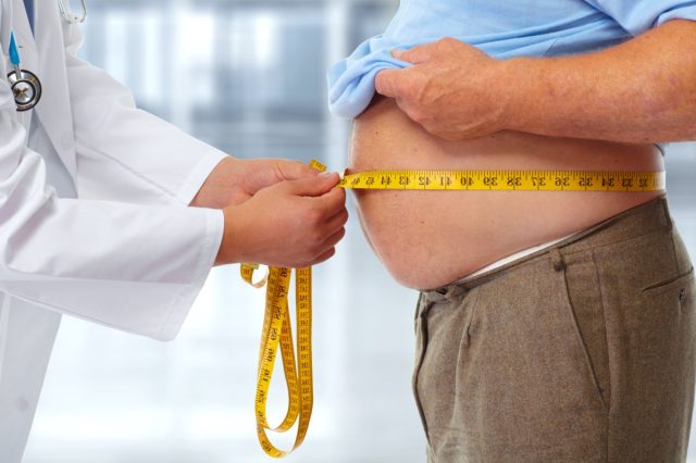 Médecin mesurant la graisse corporelle de l'homme obèse à la taille.  Obésité et perte de poids