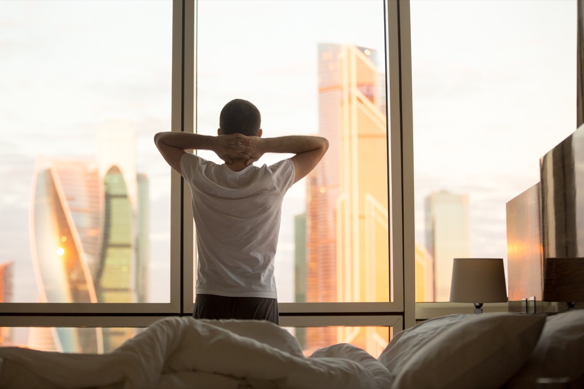 a man waking up at an inhumanly early hour and gazing out at the toronto cityscape