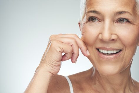smiling Caucasian senior woman with short gray hair pinching her cheek