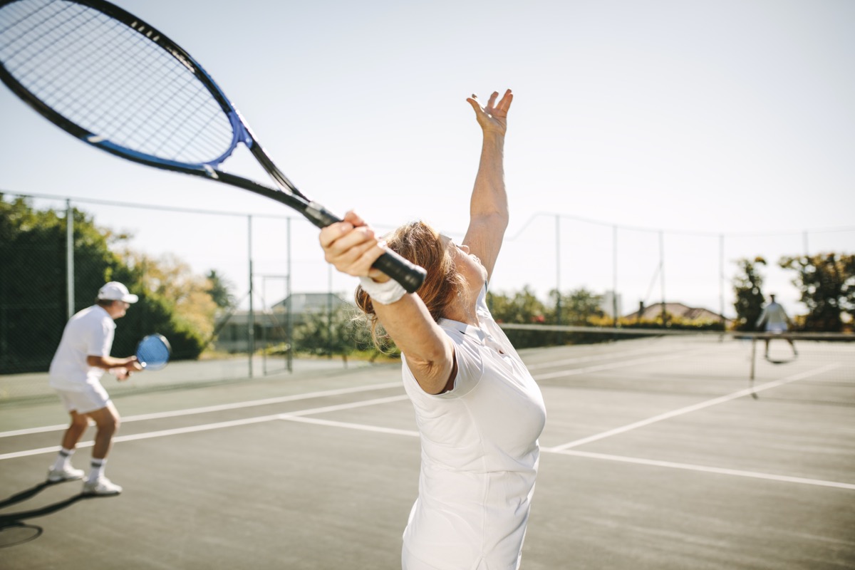 woman serving the ball while playing a mixed doubles tennis match