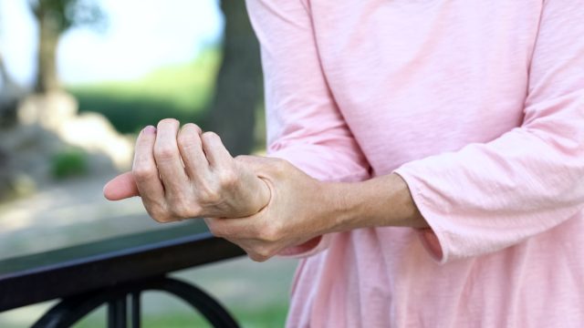 Old woman stretching numb arm, weakness of muscles in senior age, arthritis
