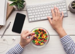 Work space with laptop, candies and woman hands