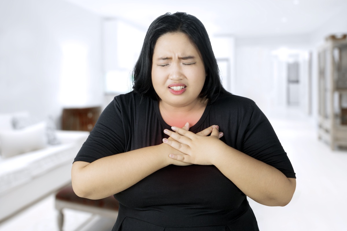 Overweight woman having a heart attack while touching her chest