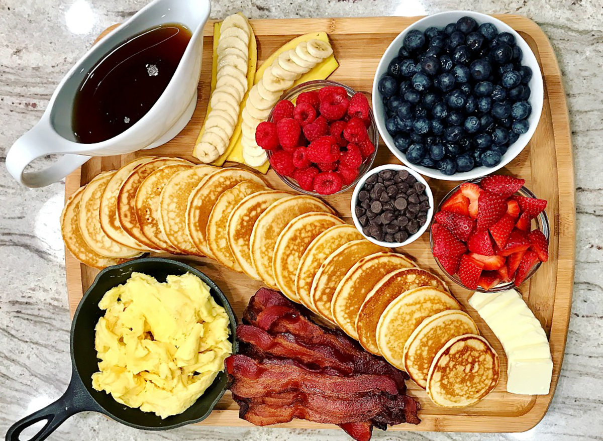 pancake board with berries chocolate chips syrup eggs bacon