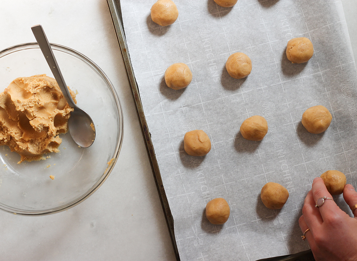 rolling up balls of peanut butter cookie dough and placing on a cookie sheet