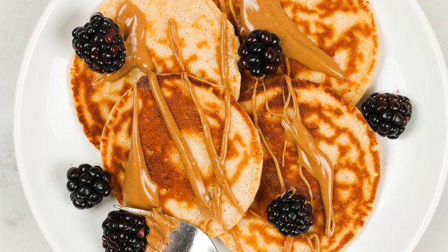 protein pancakes with peanut butter and blackberries on a white plate