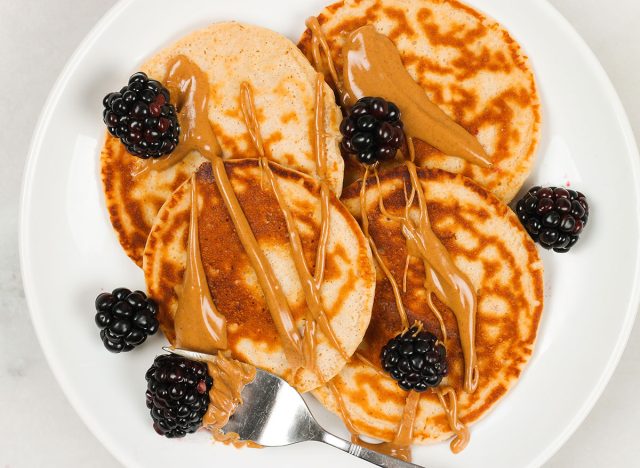 protein pancakes with peanut butter and blackberries on a white plate