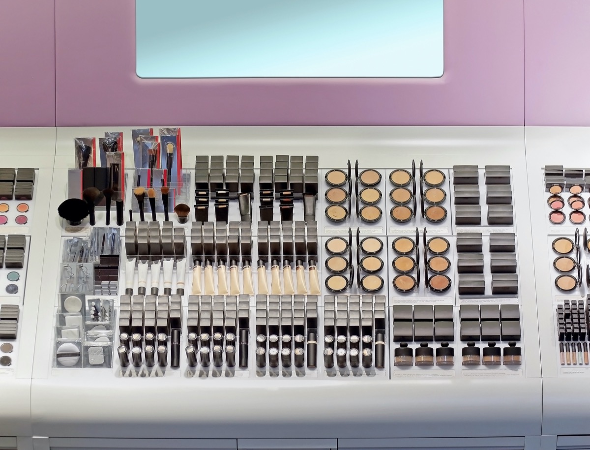 Makeup counter inside beauty store with shelf full of makeup products