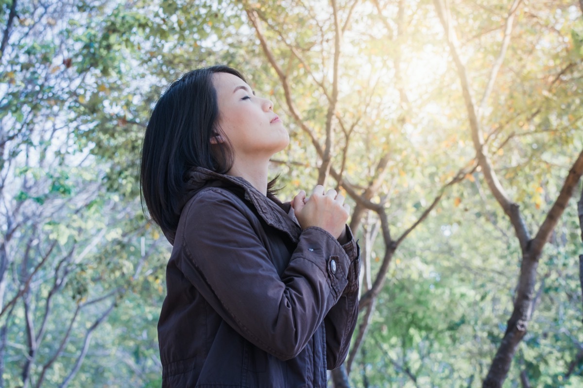 woman smiling, enjoying relaxing breathing fresh air in the garden summer sunset