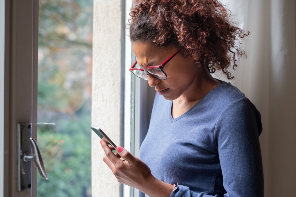 woman near window reading phone message