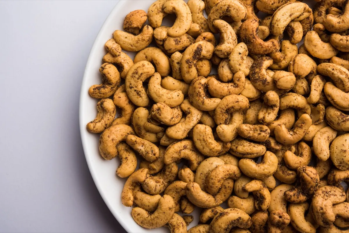spiced cashews in a white ceramic bowl against a grey background