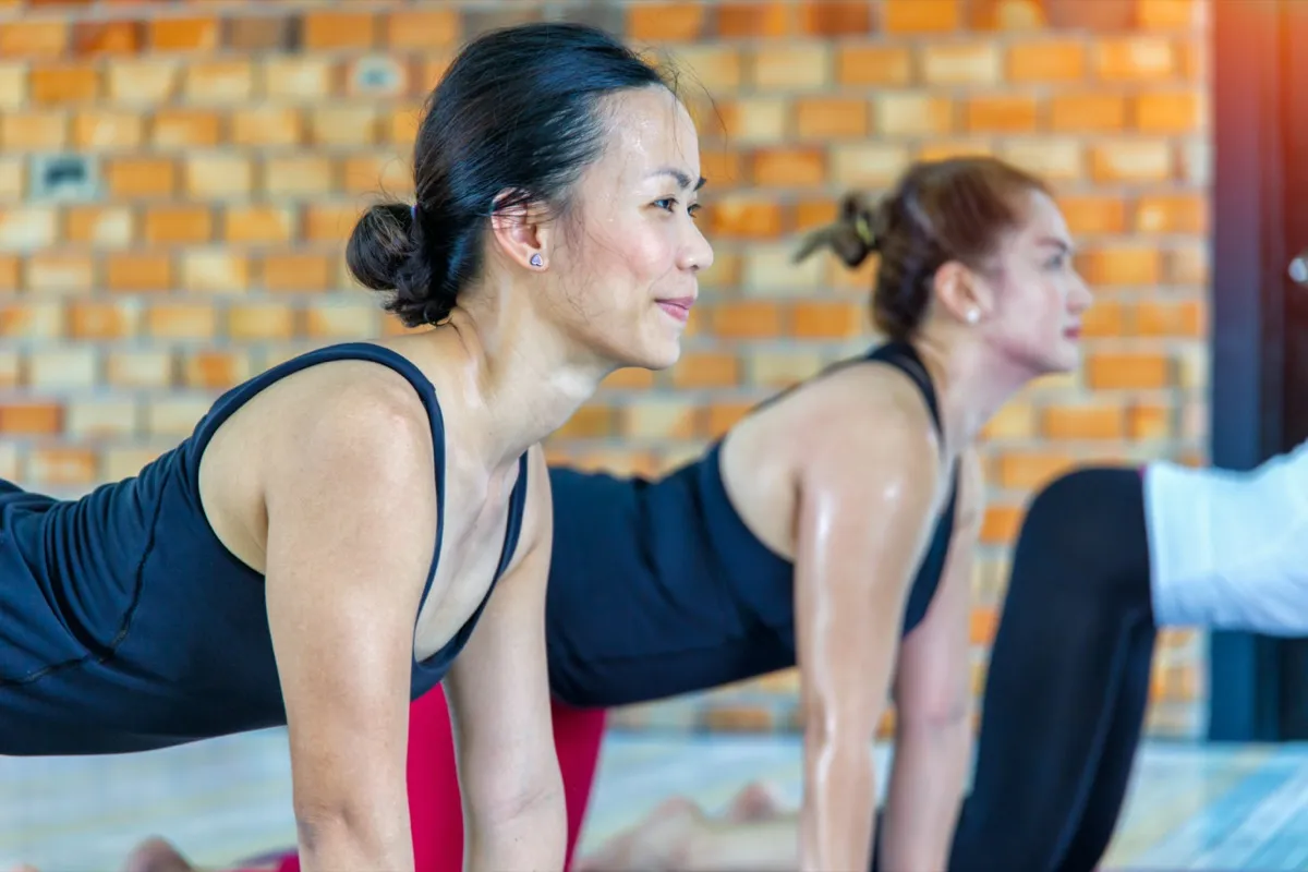 asian female group doing namaste yoga pose in row at the yoga class