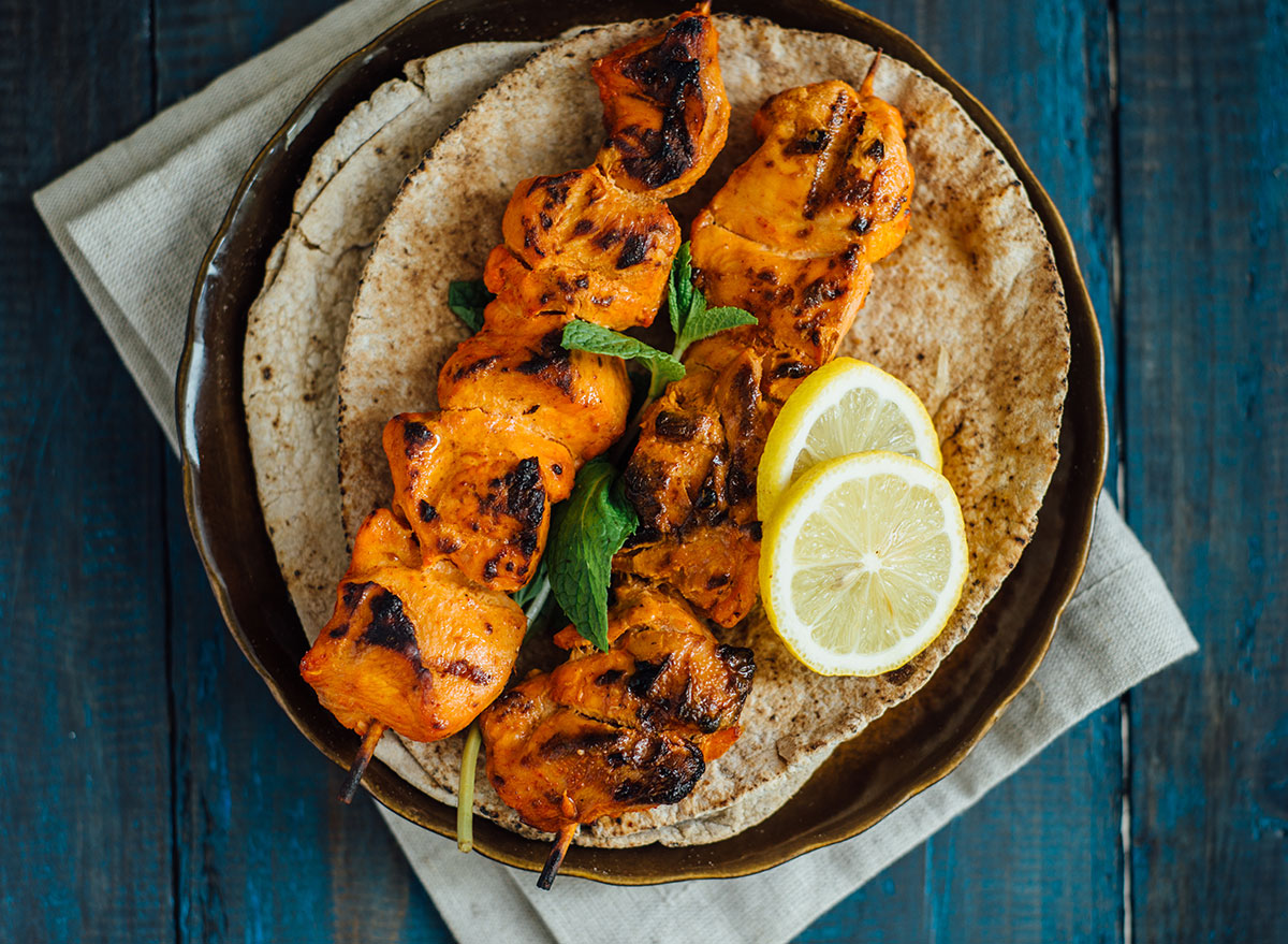 tandoori chicken skewers with lemon slices on pita