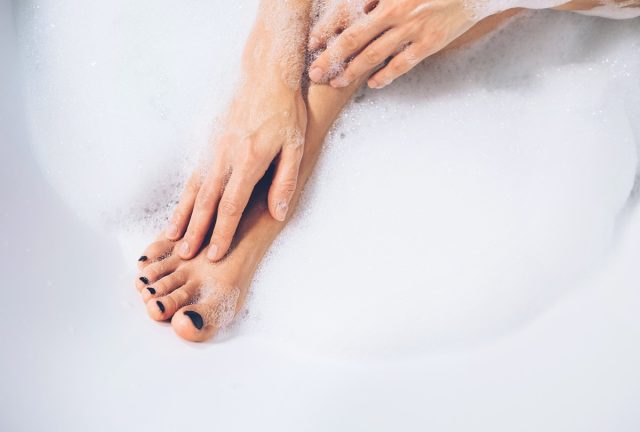 Well grooming woman's legs and hands in bath foam