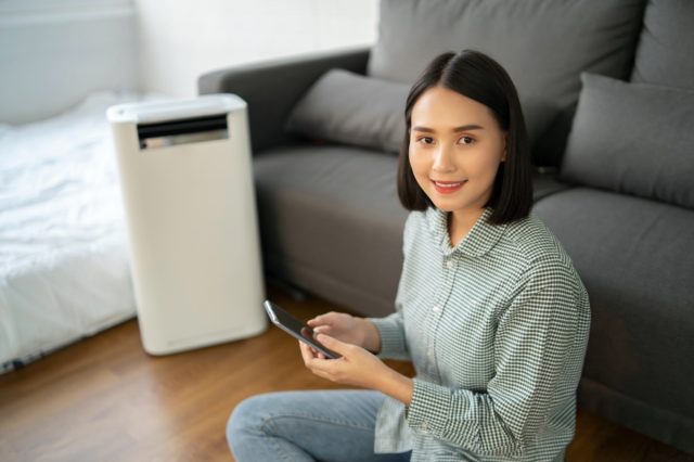 Air purifier , Asian Business woman working with laptop use phone with filter for clean room in a living room