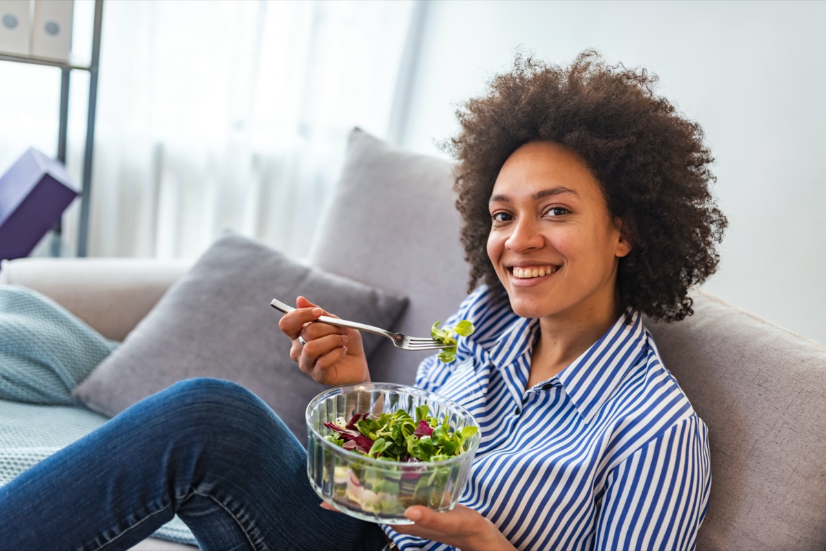 american woman eating vegetable salad at home