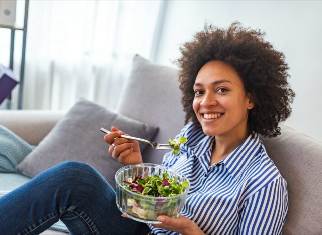 american woman eating vegetable salad at home