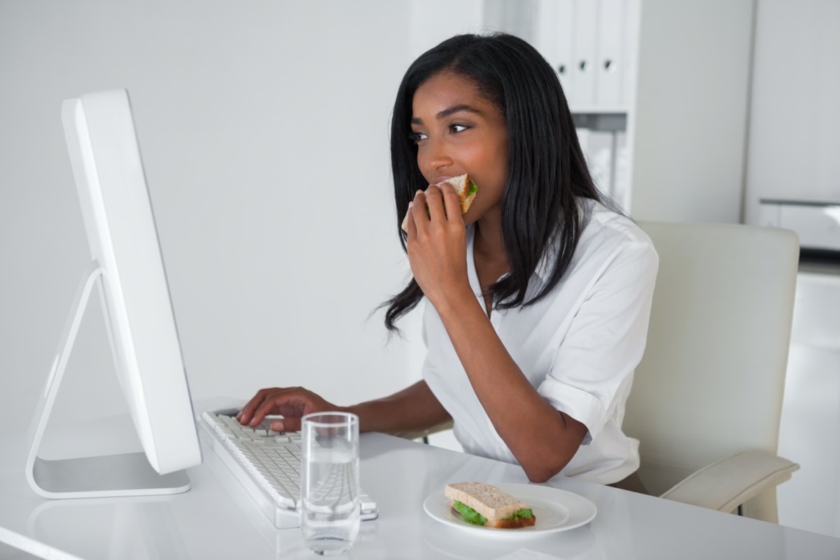 businesswoman eating a sandwich at her desk in her office