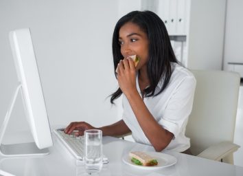 businesswoman eating a sandwich at her desk in her office
