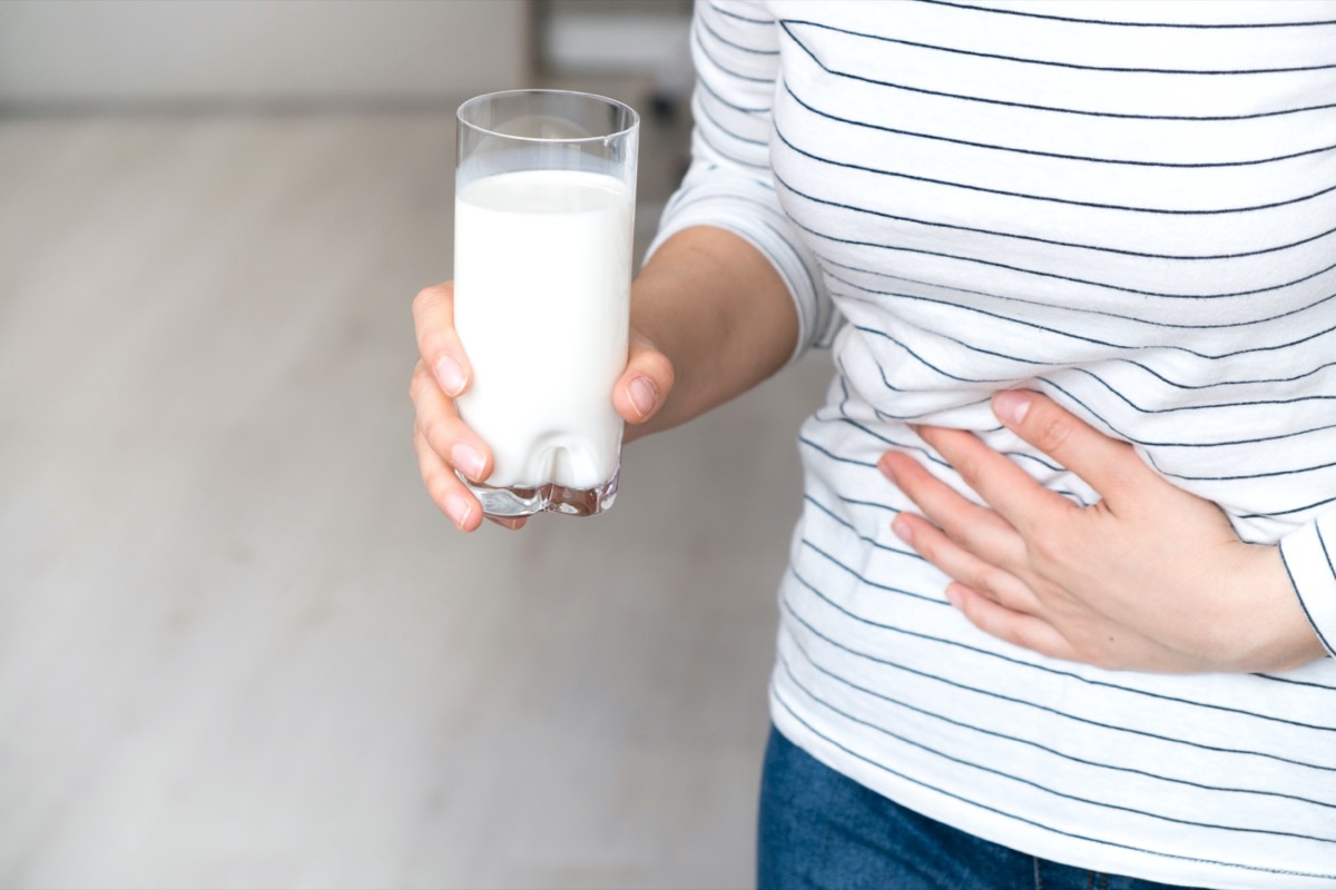 Woman holding glass of milk having bad stomach ache
