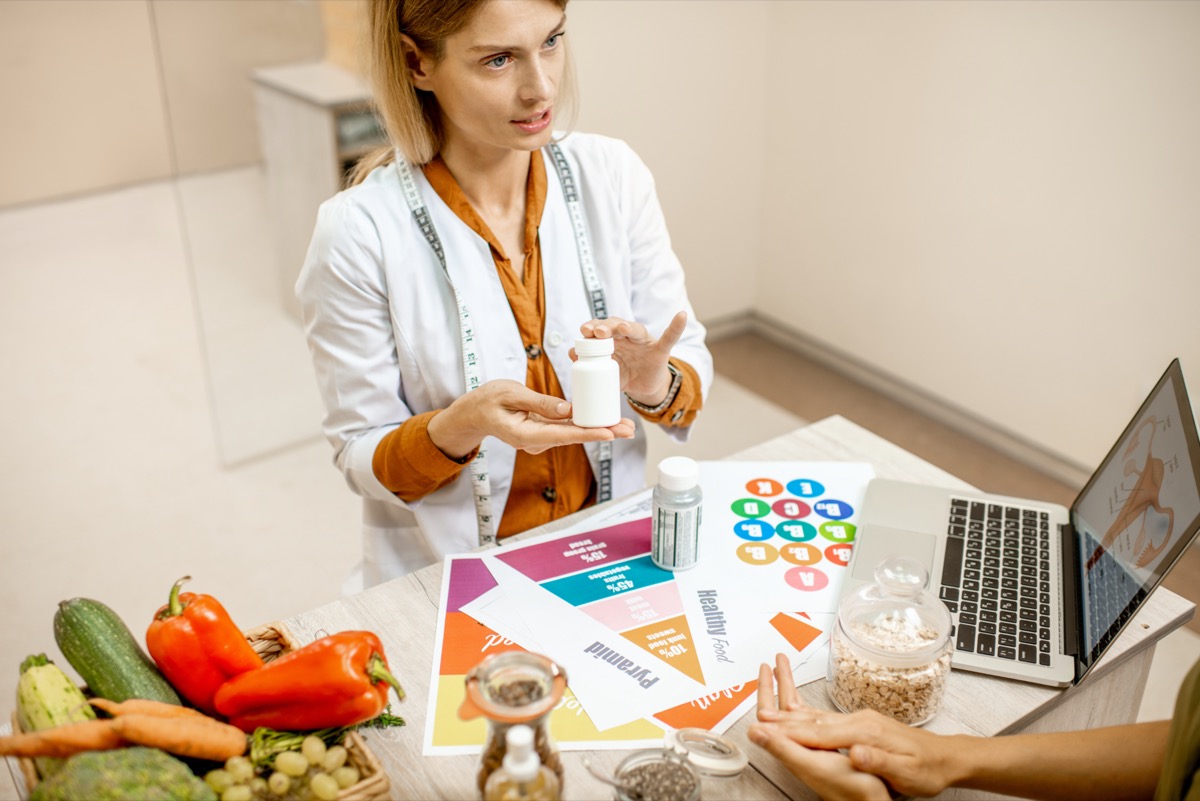 Nutritionist with young woman client talking about meal plan and healthy products during a medical consultation in the office