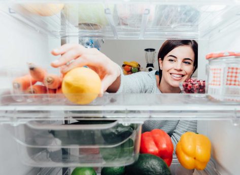 Woman reaching into fridge to grab healthy food lemon