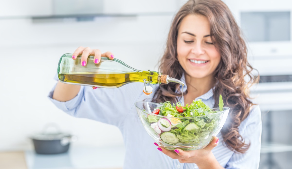 woman pouring olive oil in to the salad. Healthy lifestyle eating concept