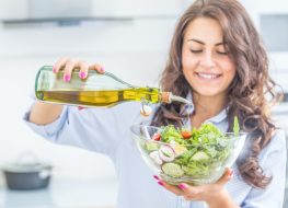 woman pouring olive oil in to the salad. Healthy lifestyle eating concept