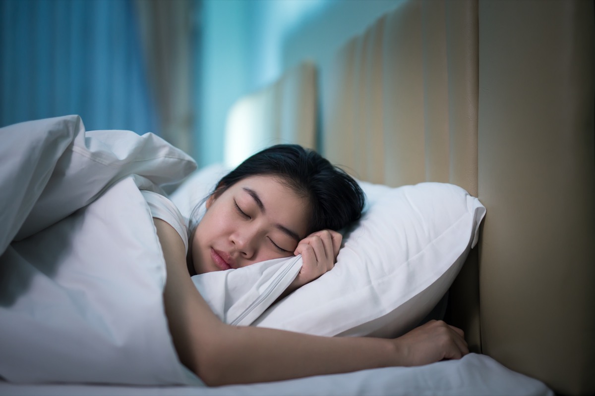 Asian woman sleeping in a bed in a dark bedroom