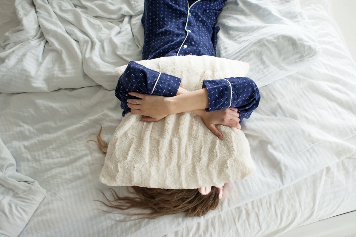woman covers her face with a pillow