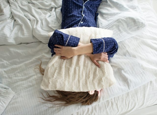 woman covers her face with a pillow
