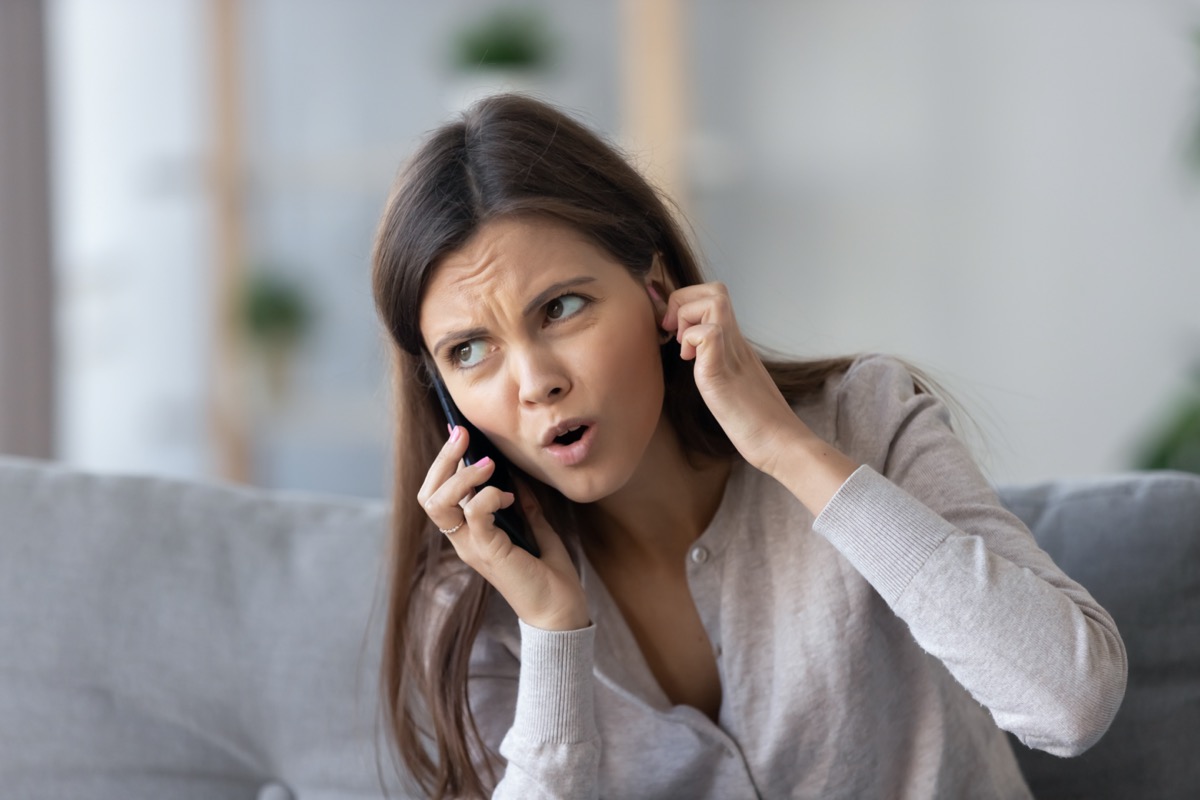 Annoyed young woman talking on the phone not hearing