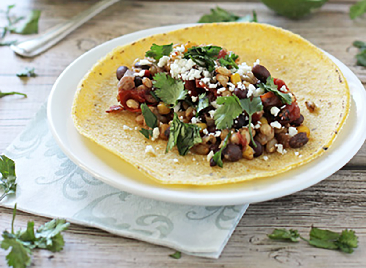 taco tortilla with barley beans cilantro and cheese on white plate