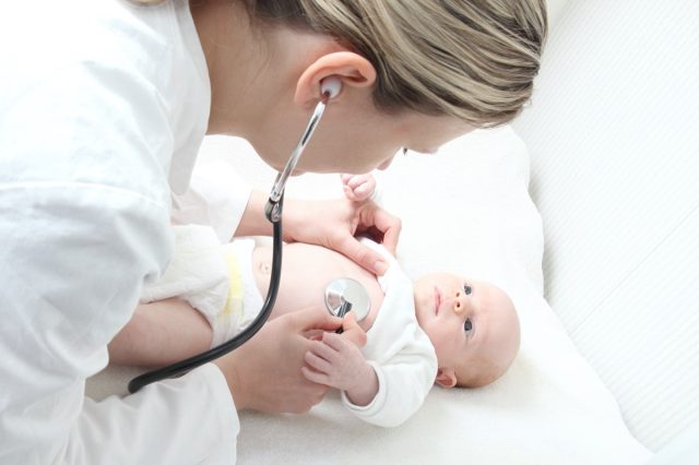 Pediatrician with baby checking for possible heart defect