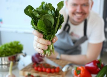 Man hold useful bunch of spinach in hand closeup on kitchen background