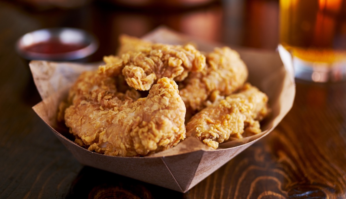 chicken fingers in a cardboard takeout basket on a wooden table