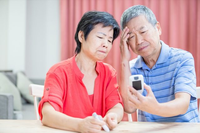 asian elder couple use blood glucose meter and worry about it
