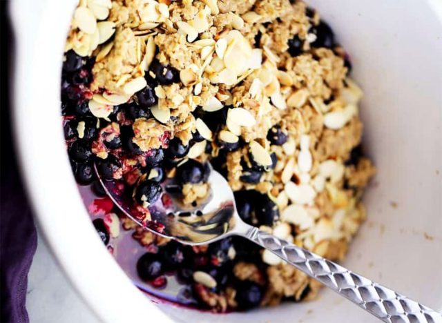 crock pot blueberry crisp in bowl with spoon