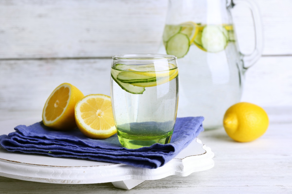 Fresh water with lemon and cucumber in glassware on wooden background