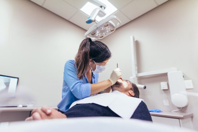 Female dentist examining a patient with tools in dental clinic