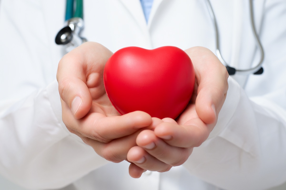 Female doctor protecting a red heart with her hands