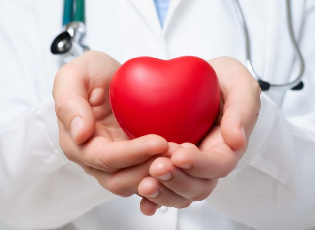 Female doctor protecting a red heart with her hands
