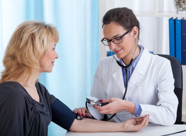female doctor taking blood pressure.