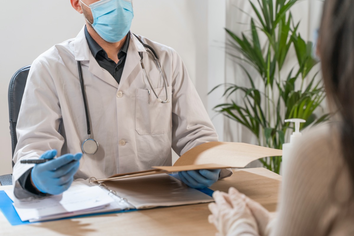 Coronavirus. Doctor visiting unhealthy woman. Doctor consults patient. They are using face mask and rubber gloves for prevention